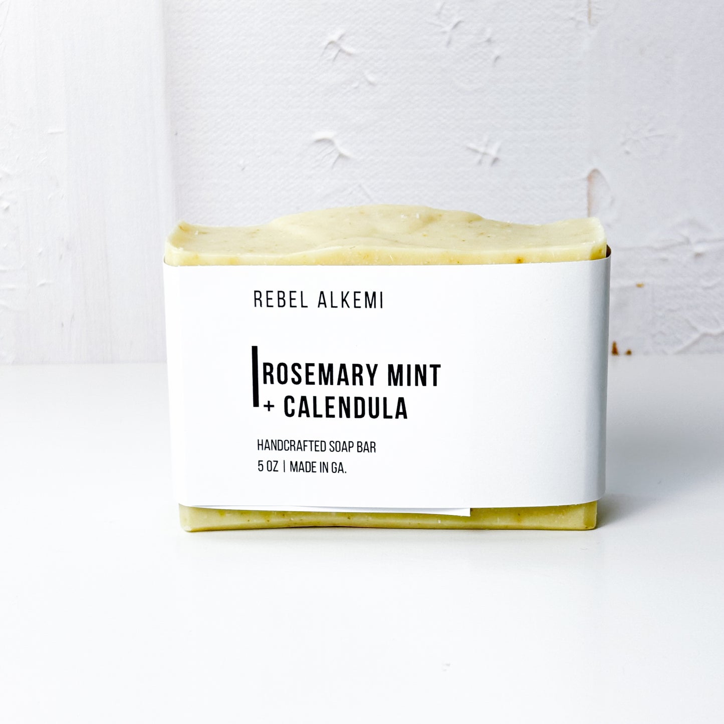 Rosemary Mint + Calendula Bar of soap with 'Rebel Alkemi' branding on a white background