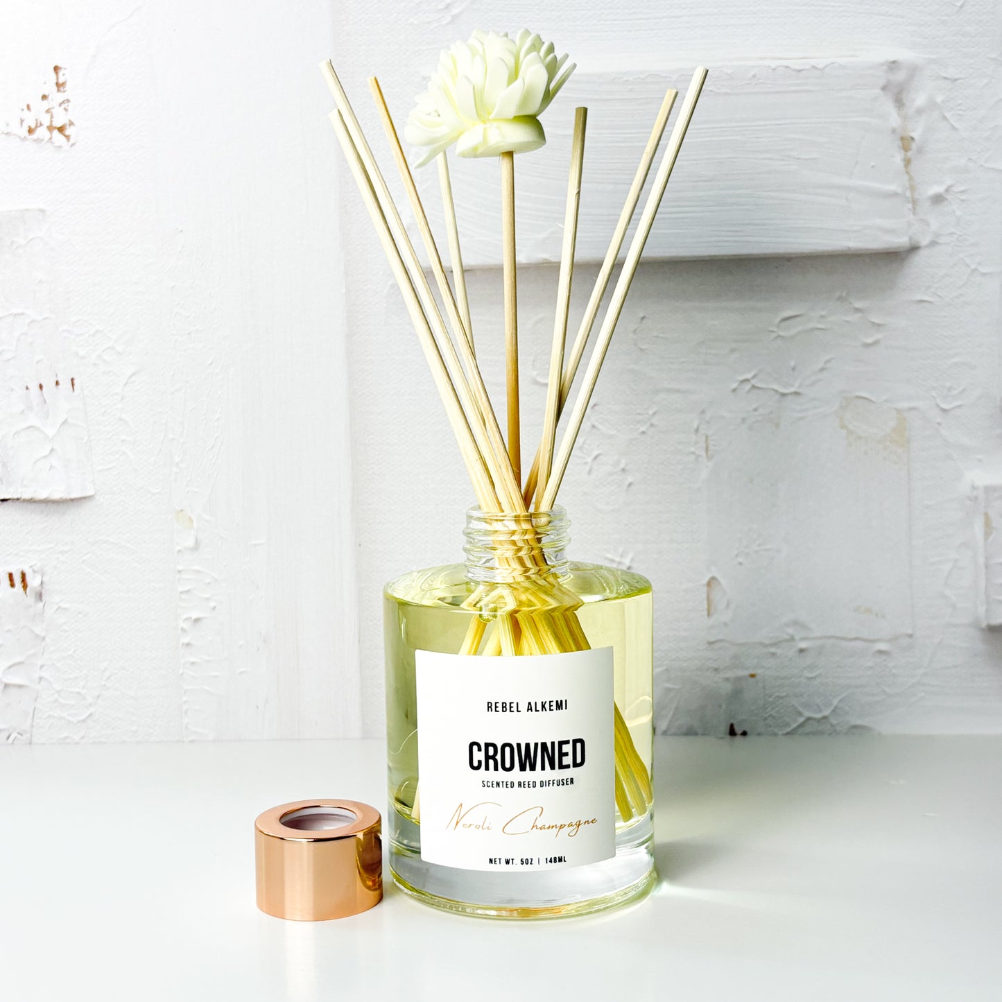 Reed_diffuser_labeled_Crowned_by_Rebel_Alkemi_on_a_white_surface_with_a_light_background.