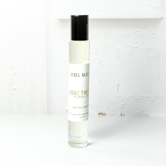 Light Theory perfume oil smells like lemon and cardamom on a white background 