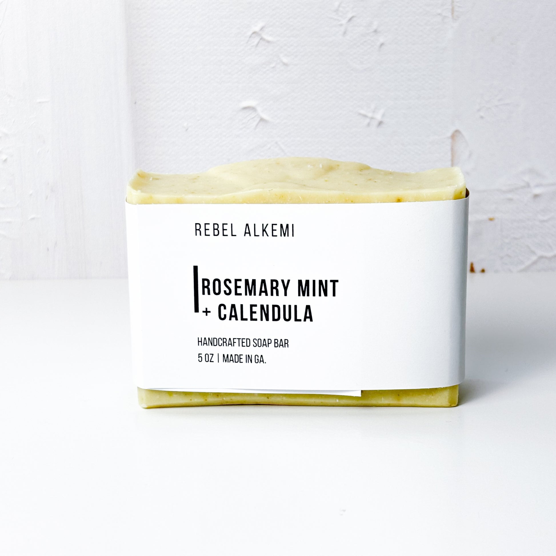 Rosemary Mint + Calendula Bar of soap with 'Rebel Alkemi' branding on a white background