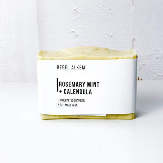 Rosemary Mint + Calendula Bar of soap with 'Rebel Alkemi' branding on a white background