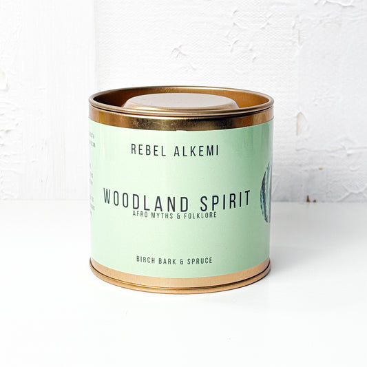 Candle in a tin labeled 'Woodland Spirit' by Rebel Alkemi on a white background